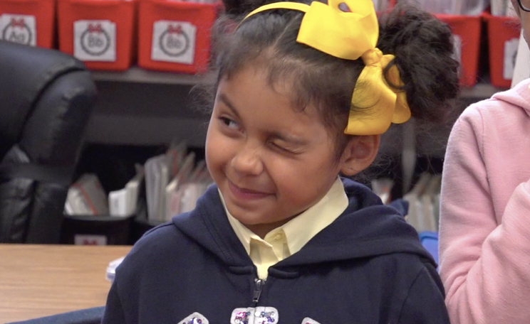 A child practices closing one eye during a facial feature warm-up game.