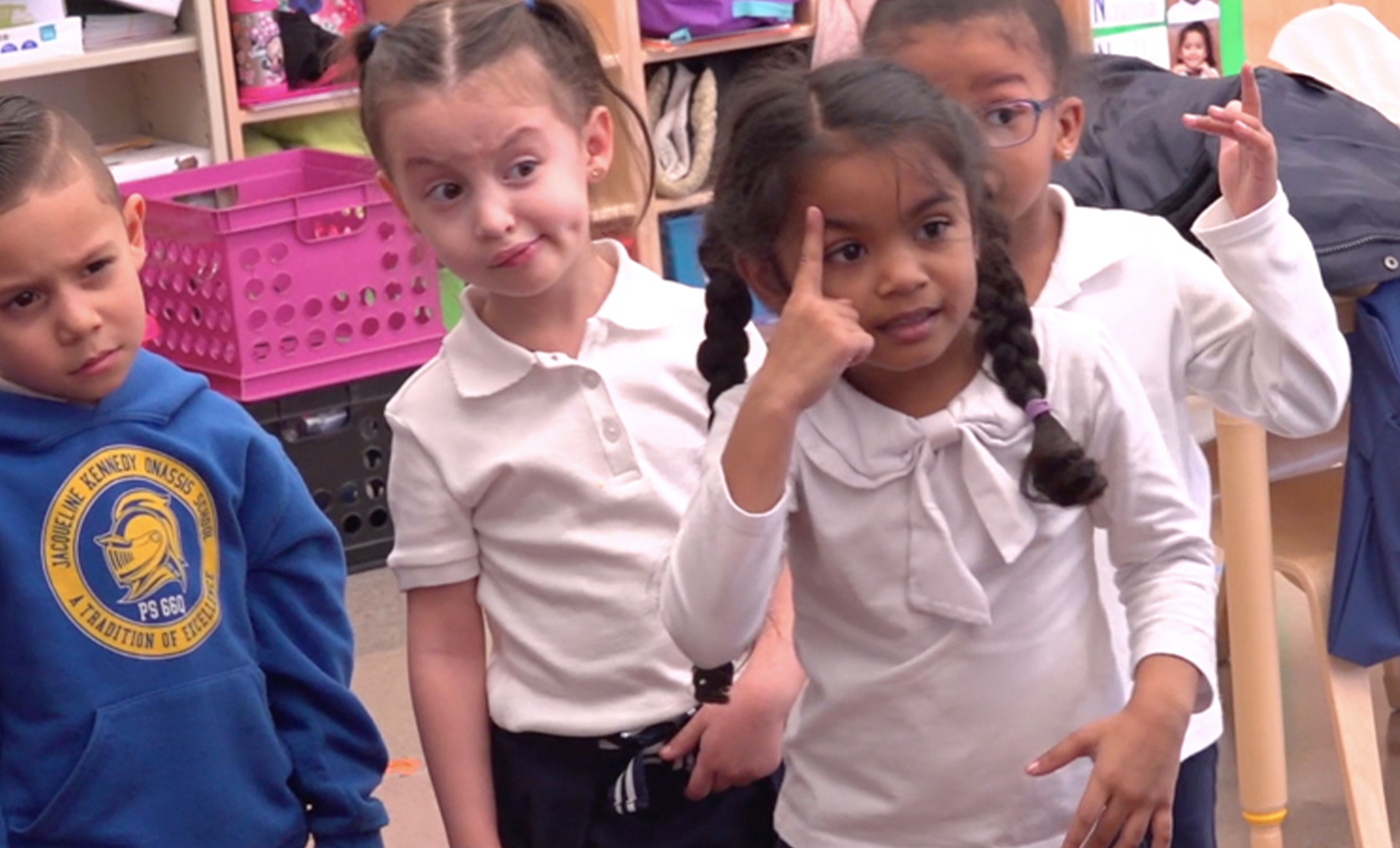 Four kindergartners pointing to and moving their eyebrows during the facial feature warmup.