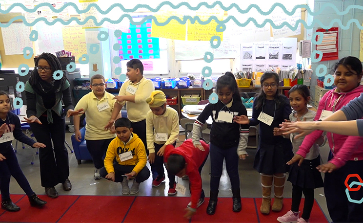 A classroom teacher and her students standing at the rug during a 5-senses journey under the water. The studentss are making a wide variety of physical choices to show what they are imagining .