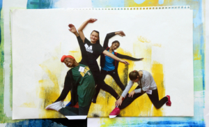 Four students pose with their bodies in dance shapes. Two are standing with one arm extended and one arm curved. One is kneeling with one arm extended up and one reaching back to her feet. One student is kneeling on one leg with her other leg extended on the floor. She is reaching both arms to that leg and her head is down.