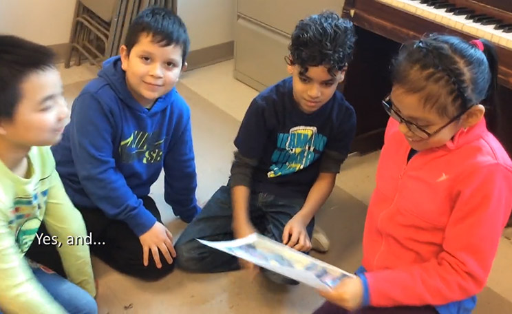 Four students gather around a reproduction of an artwork that one student holds.
