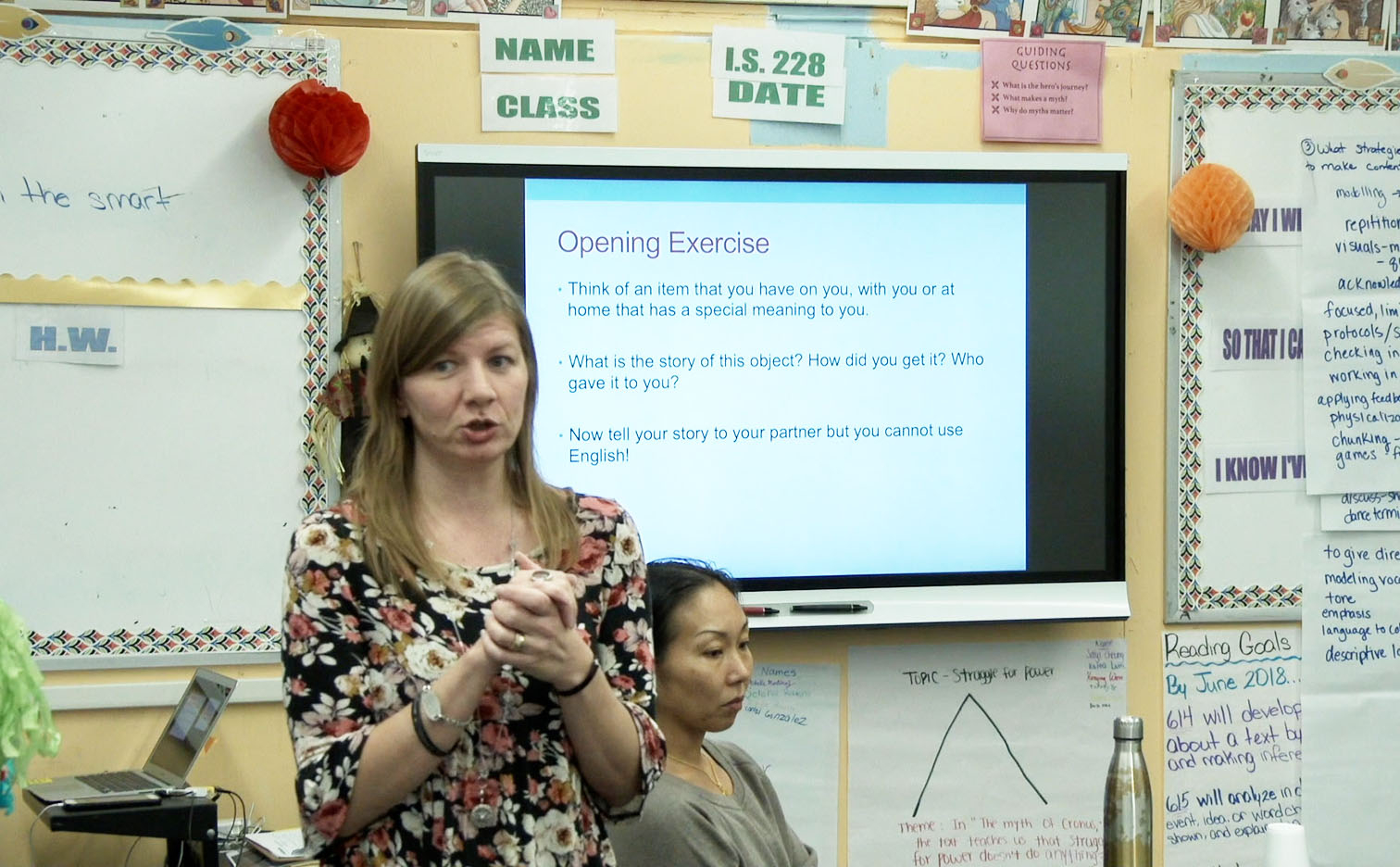 Dr Jen Mohr stands with her hands out in front of her mid sentence in front of a presentation.